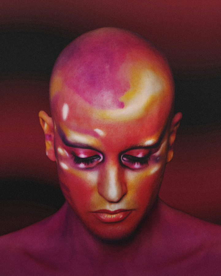 Close up portrait of Jesse with sunset colored expressive makeup with his head downward against a dark maroon background